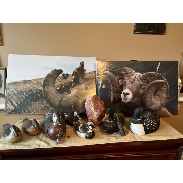collection of wooden ducks as well duck calls, and two pictures one with two photos of unknown artis