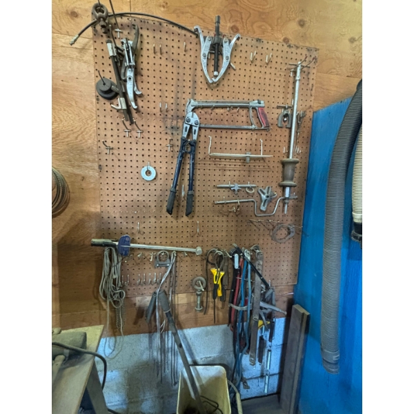 pegboard with various tools, including bolt cutters gear, polars, hacksaw, bungee cords, vice grips,