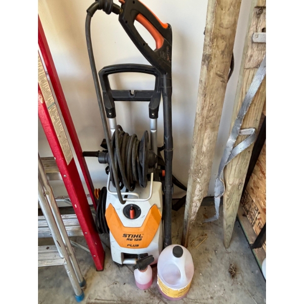 STIHL RE 129 PLUS pressure washer with a jug of washer fluid