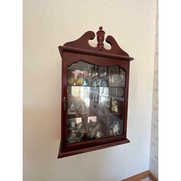 small wooden cabinet with collection of figurines and a brass spittoon .