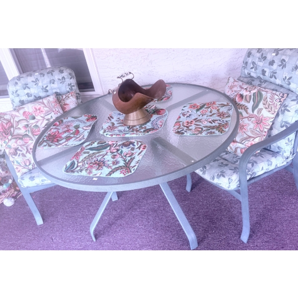 Glass Patio Table with Metal Frame, Two Chairs, Cushions, and Decorative Accents