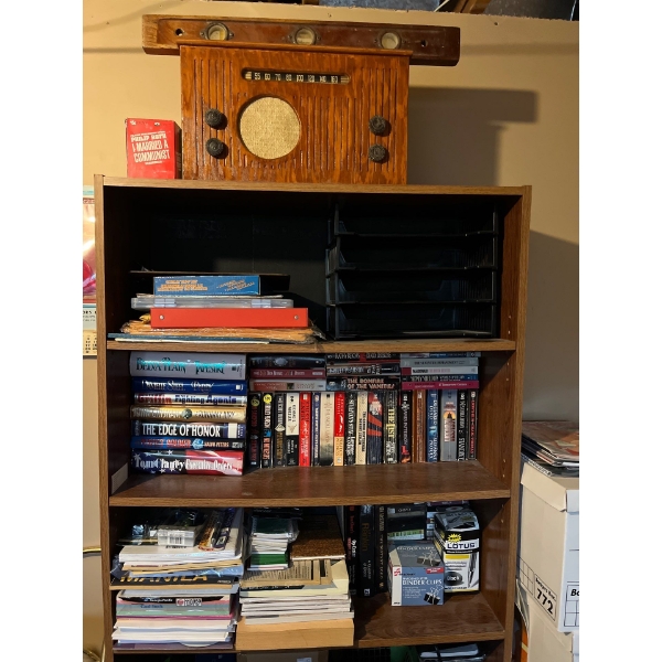 Shelf with a number of books, office supplies, printer with printer ink still with storage underneat