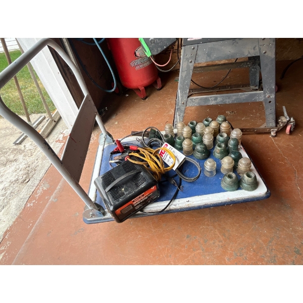 cart with battery charger and jumper cables with a selection of antique power line insulators .