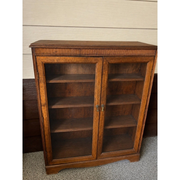 A dark wood, two-door cabinet with glass panels designed to showcase delicate collectibles 

44”L x 