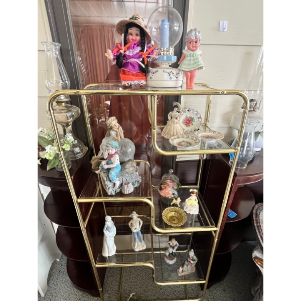 Collection of vintage figurines, dolls, and decorative items displayed on a brass and glass etagere,
