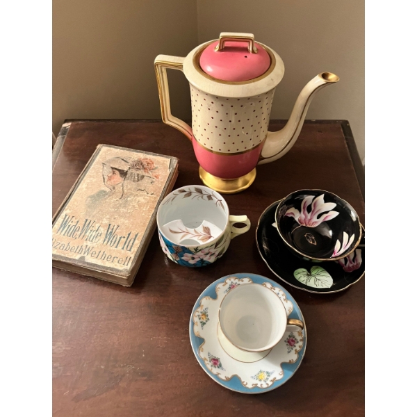 Cup and saucer saucer, set with tea, pot sugar bowl and a book called wide wide world by Elizabeth W