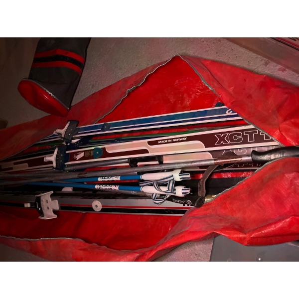 collection of vintage cross country skis with poles, including vintage bag and vintage cross country
