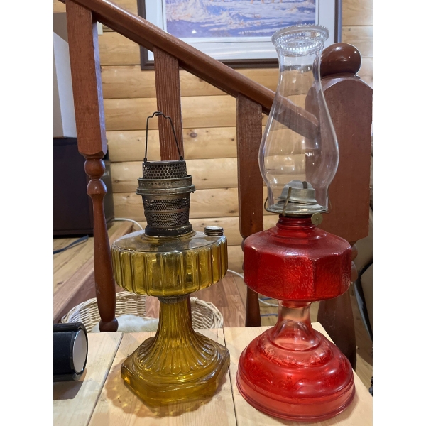  two oil lanterns with coloured bases, one red and one yellow the red one has the glass and the yell