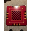Image 2 : Square wooden game board featuring a central checkerboard in red and black, bordered by backgammon m