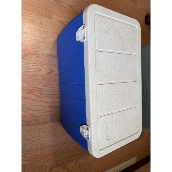 Coleman cooler featuring a blue plastic body and a white removable hinged lid, equipped with secure 