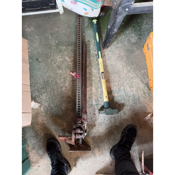 Hi-Lift mechanical farm jack with a steel frame and a yellow-handled sledge hammer Manufacturer deta