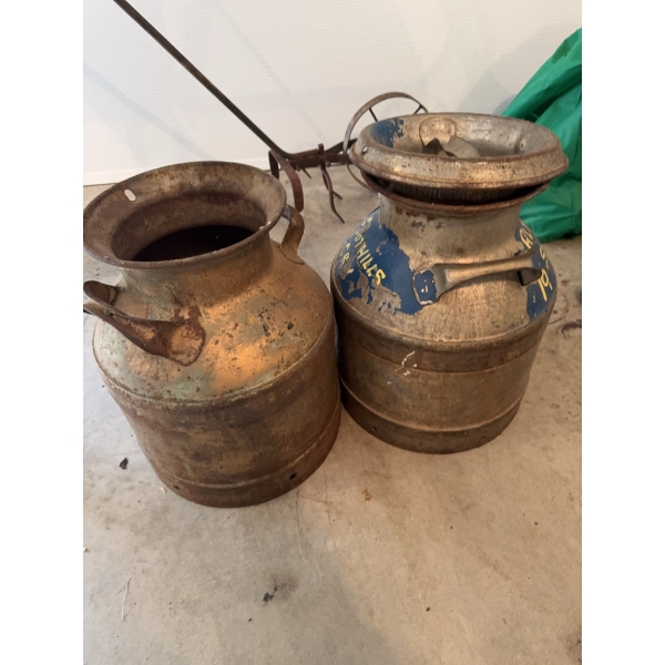 Two vintage metal milk churns. One churn is painted with blue and has yellow lettering "A.S. ALFRED 