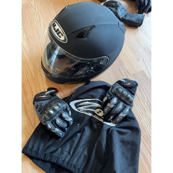HJC full-face black motorcycle helmet with visor, a pair of Teknic armored gloves, and black leather