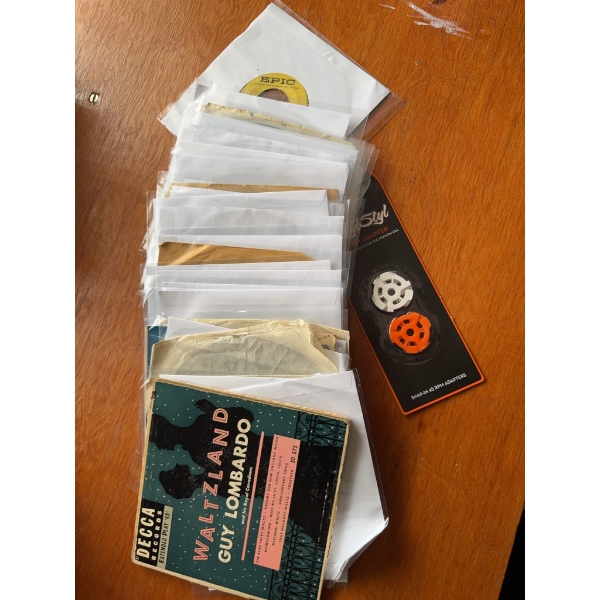 45 RPM vinyl records with sleeves, Decca Waltzland by Guy Lombardo, and a package of 45 RPM spindle 