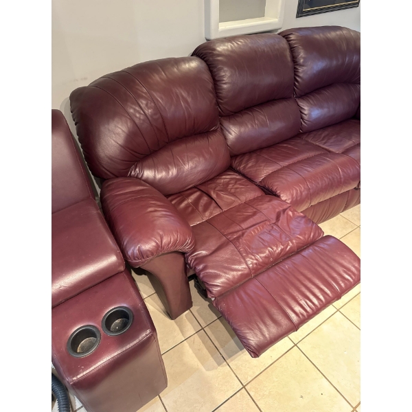 burgundy leather reclining sofa features a center console with built-in cup holders. 
