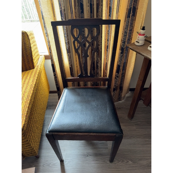Wooden chair featuring a carved openwork backrest and a black vinyl upholstered seat. The chair has 