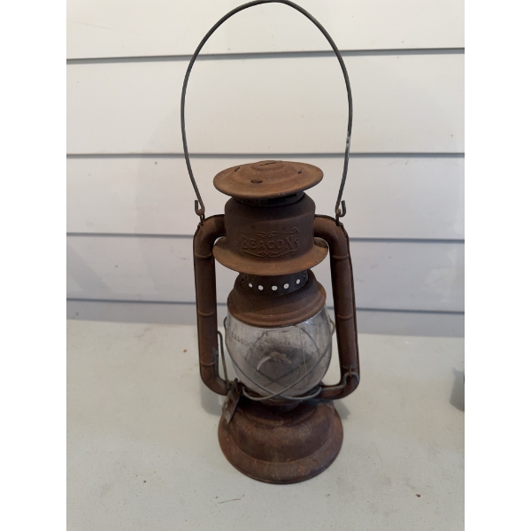 Beacon kerosene lantern made of metal with a clear glass globe and wire handle. Shows surface rust a