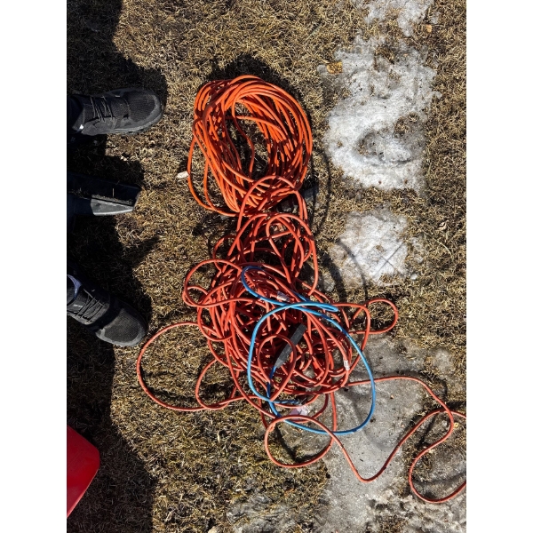 Two very long extension cords orange and a blue short one multi plug.