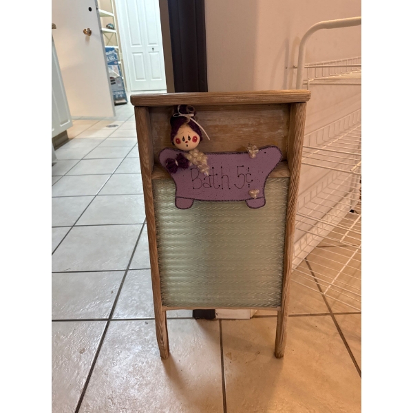 rustic wall hanging made to resemble a washboard, featuring a doll and a sign that reads "Bath 5¢".