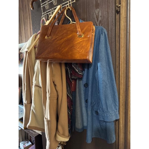  vintage jacket, vintage shirt, and leather purse, and walking cane hanging on door.