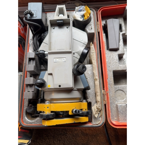 Sokkia surveying instrument housed in a fitted hard case, including power supply and accessories. Th