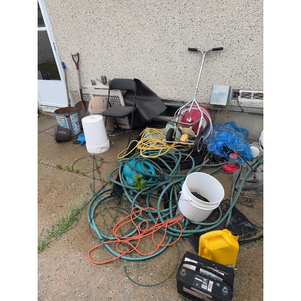 Various outdoor tools and garden equipment such as hoses, buckets, plastic containers, extension cor