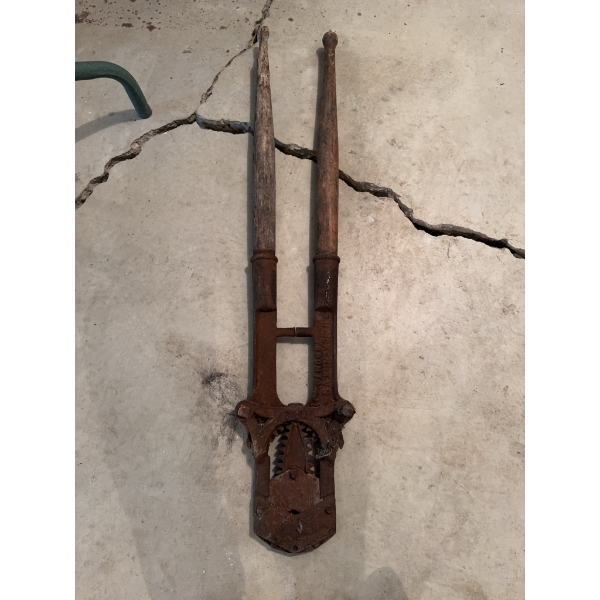 Antique post hole digger with cast iron mechanical components and wooden handles. Designed for manua