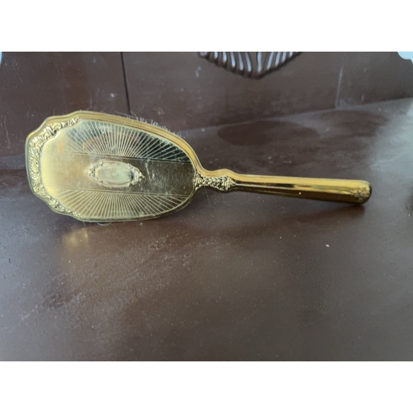 Gold-tone decorative hairbrush featuring ornate detailing on the back and handle and synthetic brist