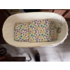 Image 2 : White wicker baby bassinet with folding legs, lace trim, fitted colorful smiley face fabric, and thr
