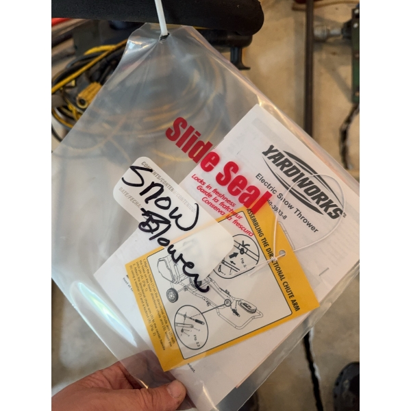 Yardworks electric snow thrower with attached yellow extension cord. Includes instruction manual and