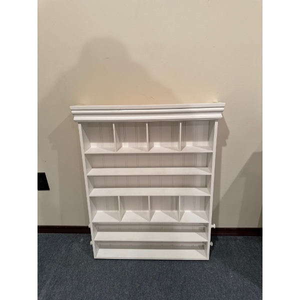 This white wall-mounted shelf is a decorative display unit, likely used for organizing small items s