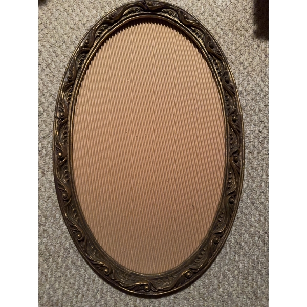 Oval metal frame with decorative floral design, containing a black and white photographic portrait o