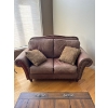 Image 1 :  Brown leather loveseat with rustic nailhead trim along the rolled arms and base.