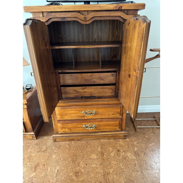  vintage wood armoire with decorative wheat carvings on the doors and brass-colored hardware.