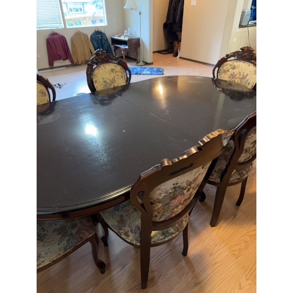 Dining set featuring an oval-shaped wooden table with dark finish and leaf extensions, accompanied b