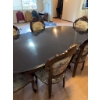 Image 1 : Dining set featuring an oval-shaped wooden table with dark finish and leaf extensions, accompanied b
