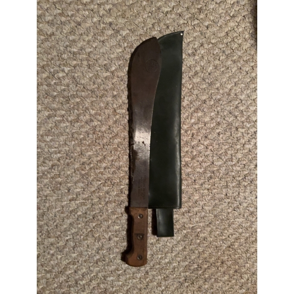 Tramontina hand-forged bolo machete, made in Brazil, featuring a wooden handle and green sheath. The