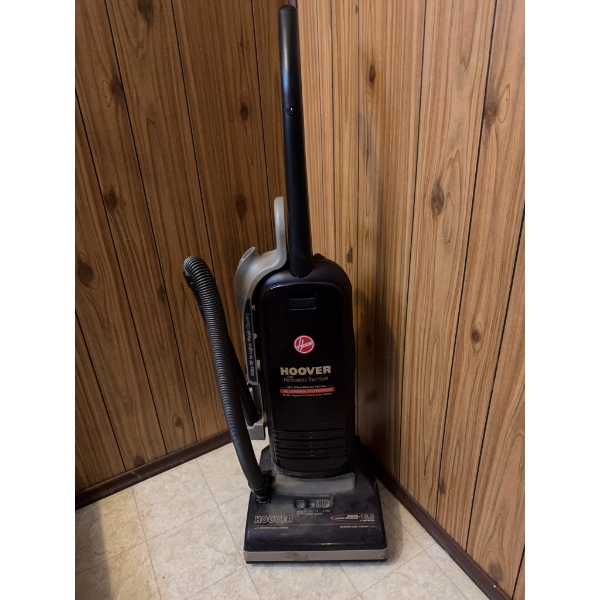 Hoover WindTunnel upright vacuum cleaner with attached hose. Features multi-stage filtration and Win