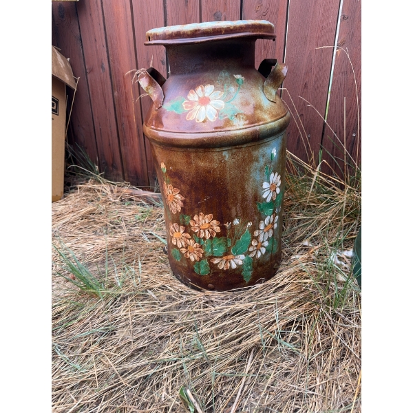 Two metal milk cans. One is decorated with hand-painted flower designs, and the other is solid green