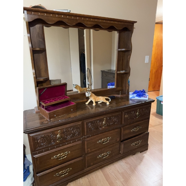 This vintage-style wooden dresser features ornate carved drawer fronts, brass-colored handles, and a