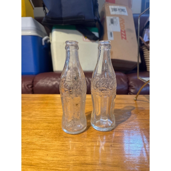 vintage clear glass Coca-Cola bottles featuring the iconic hobbleskirt contour design. 