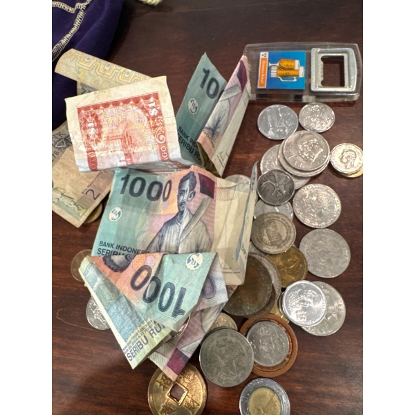 Various foreign money pile and crown royal bag with bottle opener.