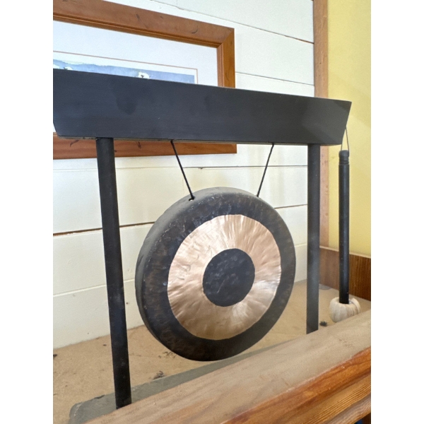 A Woodstock Chimes percussion desk gong. It features a bronze gong suspended from a contemporary bla