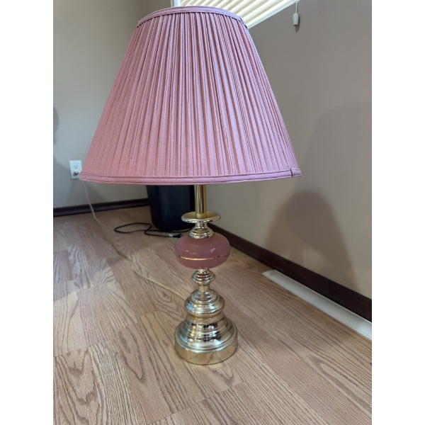 Table lamp featuring a brass base and column with a round pink glass accent, topped by a pleated pin
